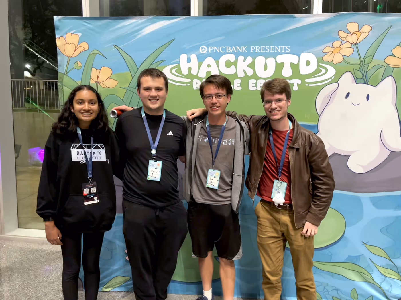 My team poses in front of a HackUTD banner. I discretely hold an energy drink in my right hand.