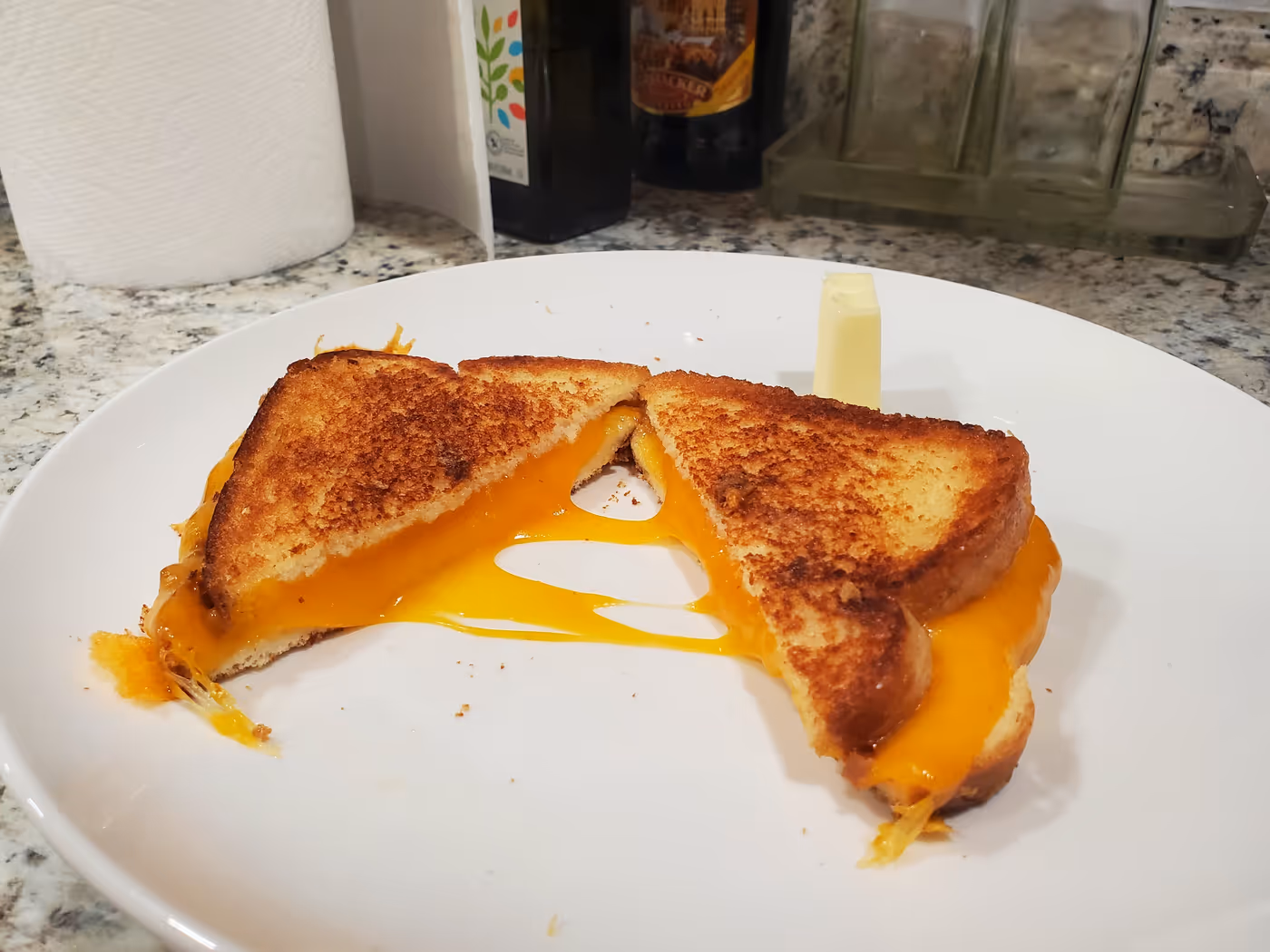 a grilled cheese sandwich cut in half diagonally with cheese dripping out