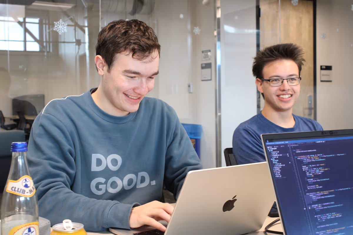 two students work on their laptops in a university building